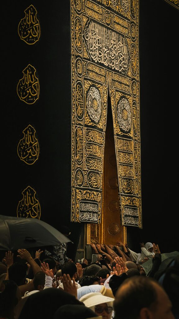 A crowd of pilgrims reaching towards the sacred Kaaba door in Mecca, Saudi Arabia.